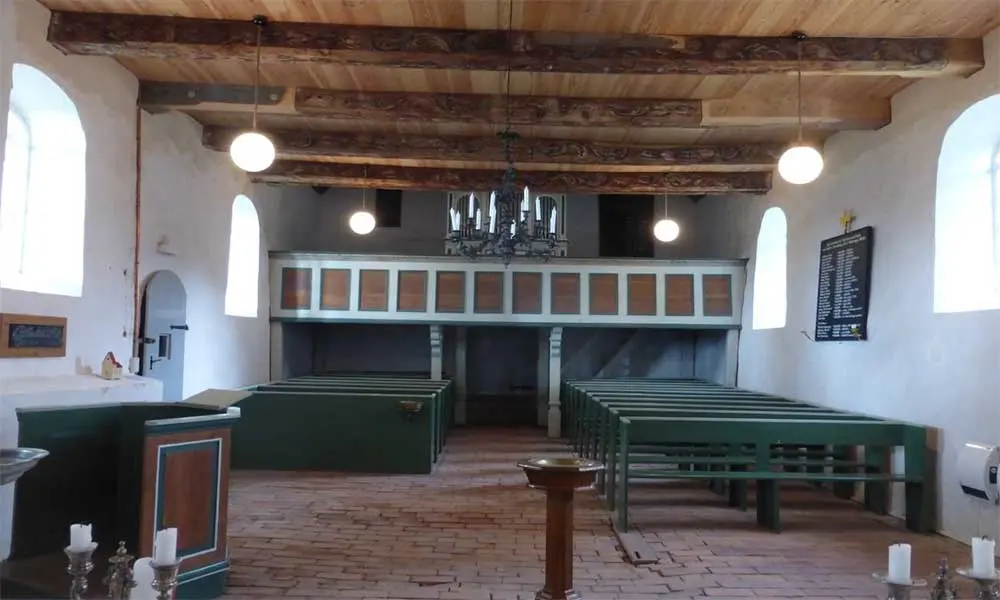 Kirchenschiff (nach Westen) mit Gest&uuml;hl und Orgelempore. Die abgesackten Ziegel sind gut erkennbar.
